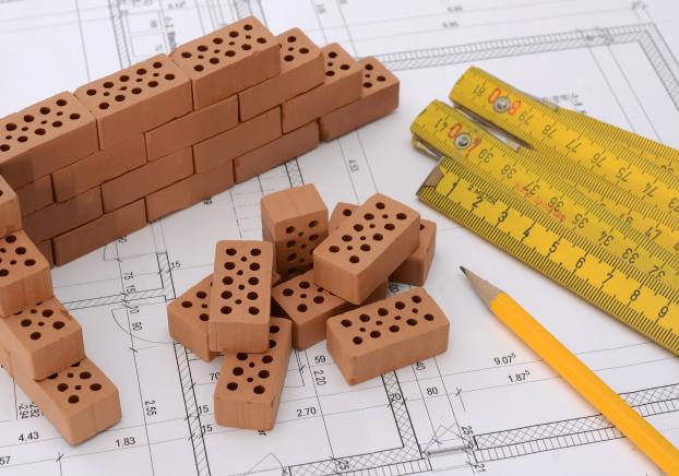 Miniature bricks arranged on a blueprint with a pencil and a ruler