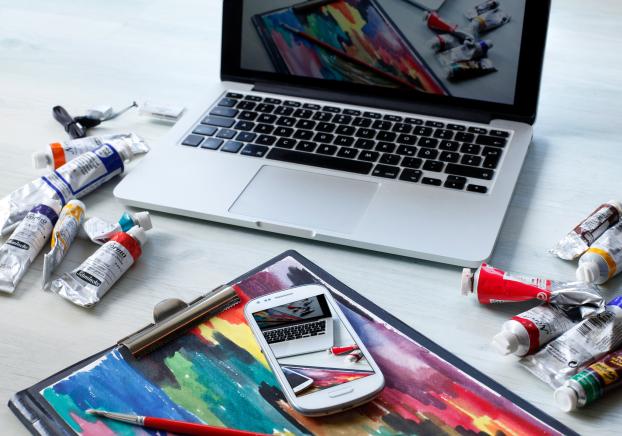 Paint arranged around a painting and a laptop
